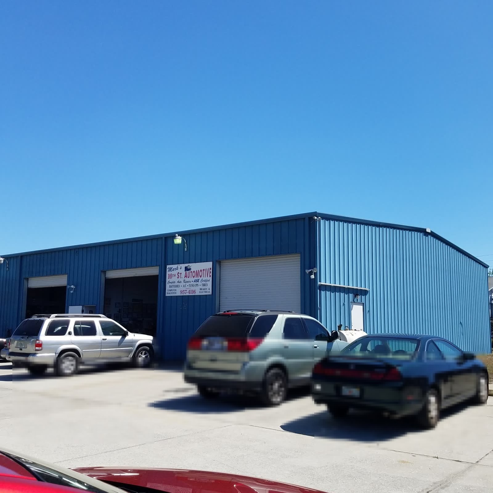 Blue metal shop with three bays and Mark’s 10th Street Automotive sign on Eastern Ave